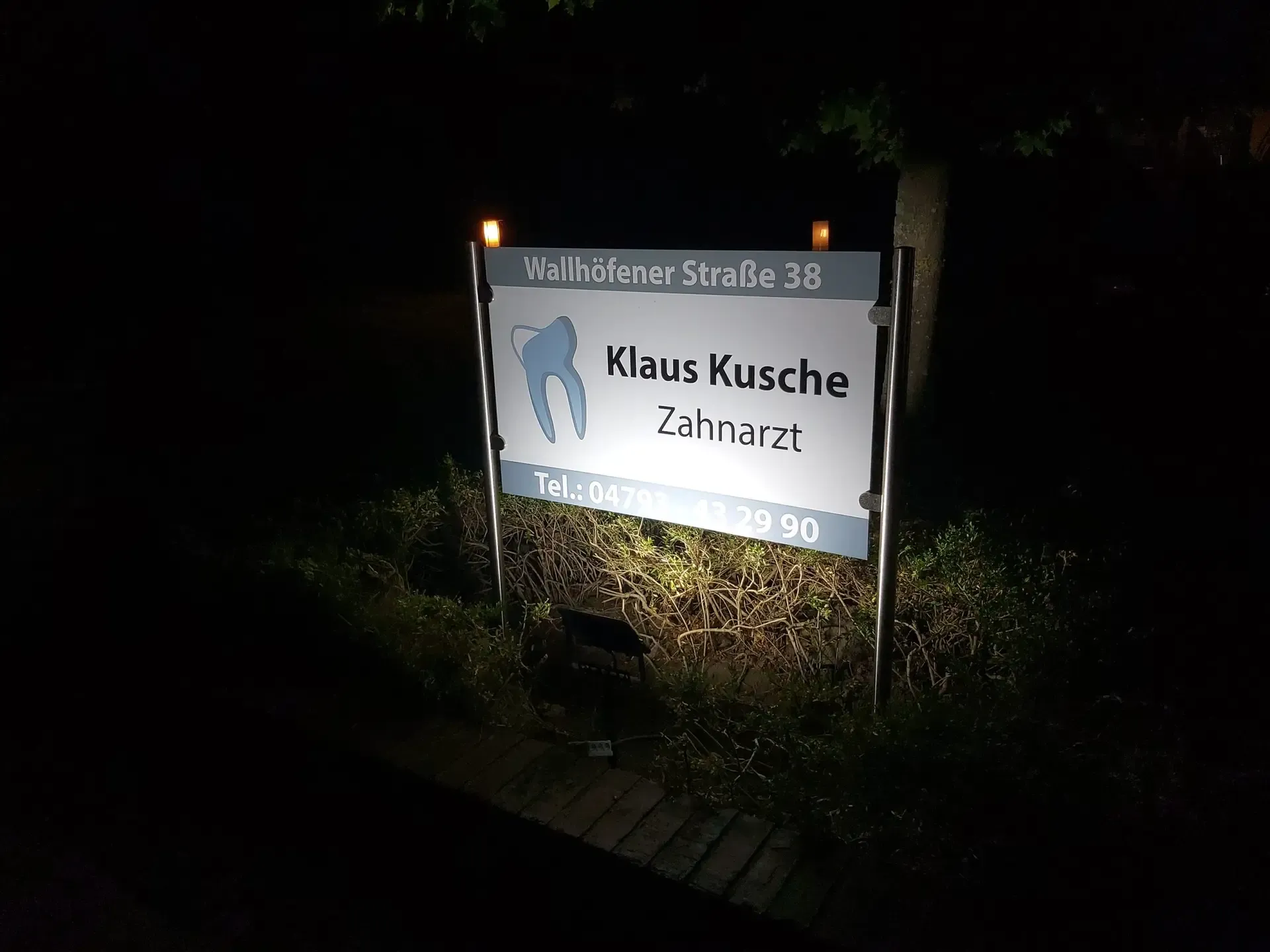 Beleuchtetes Praxisschild bei Nacht