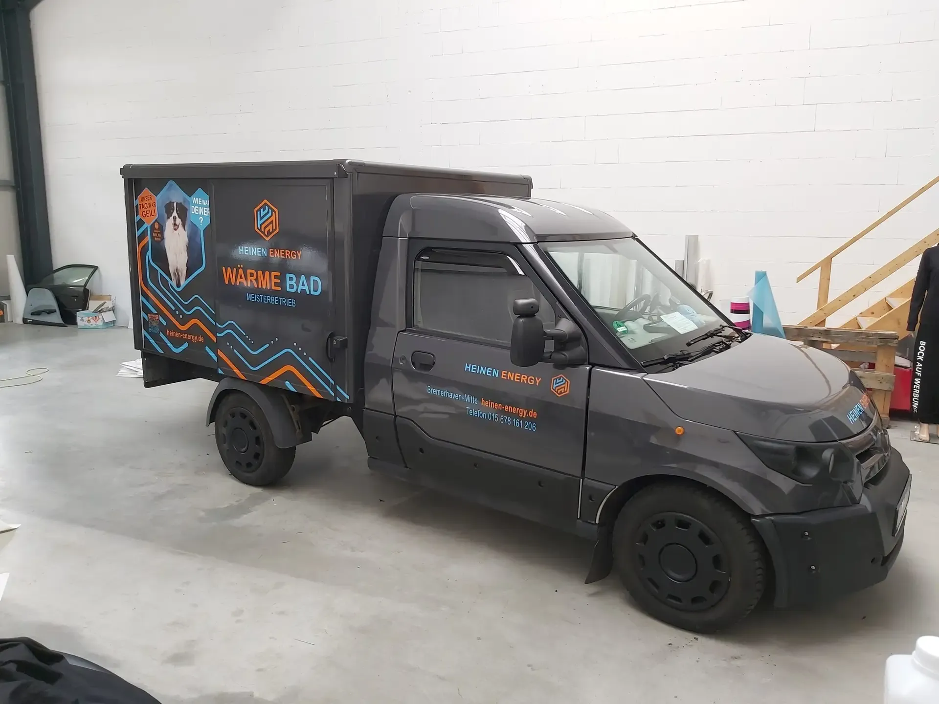 Dunkler Elektrotransporter mit Fahrzeugfolierung in der Halle