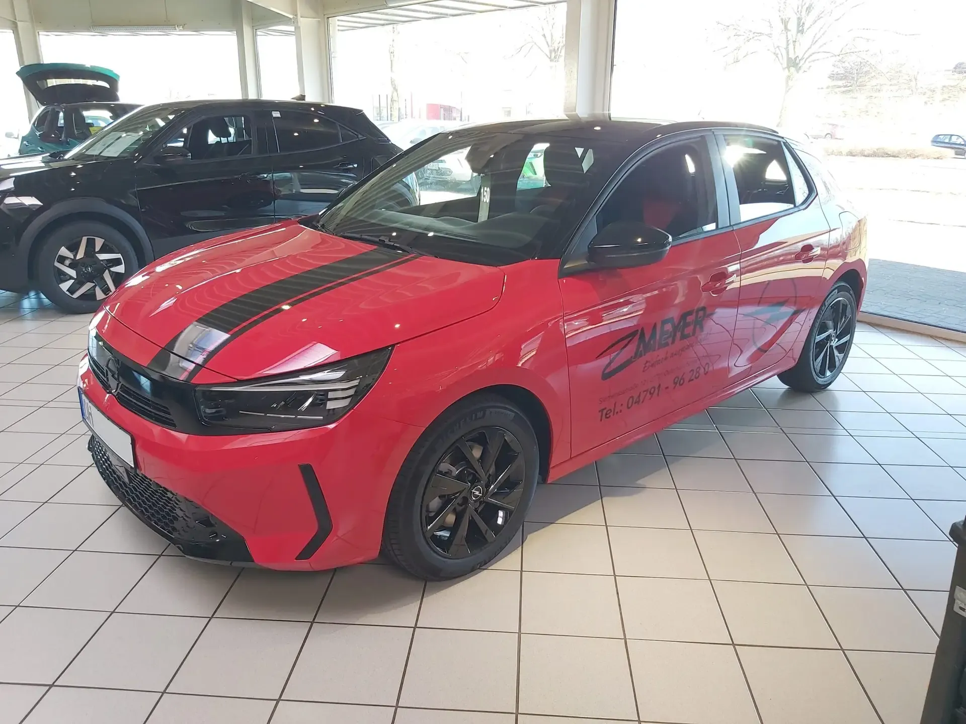 Roter Kleinwagen mit schwarzen Designstreifen im Autohaus