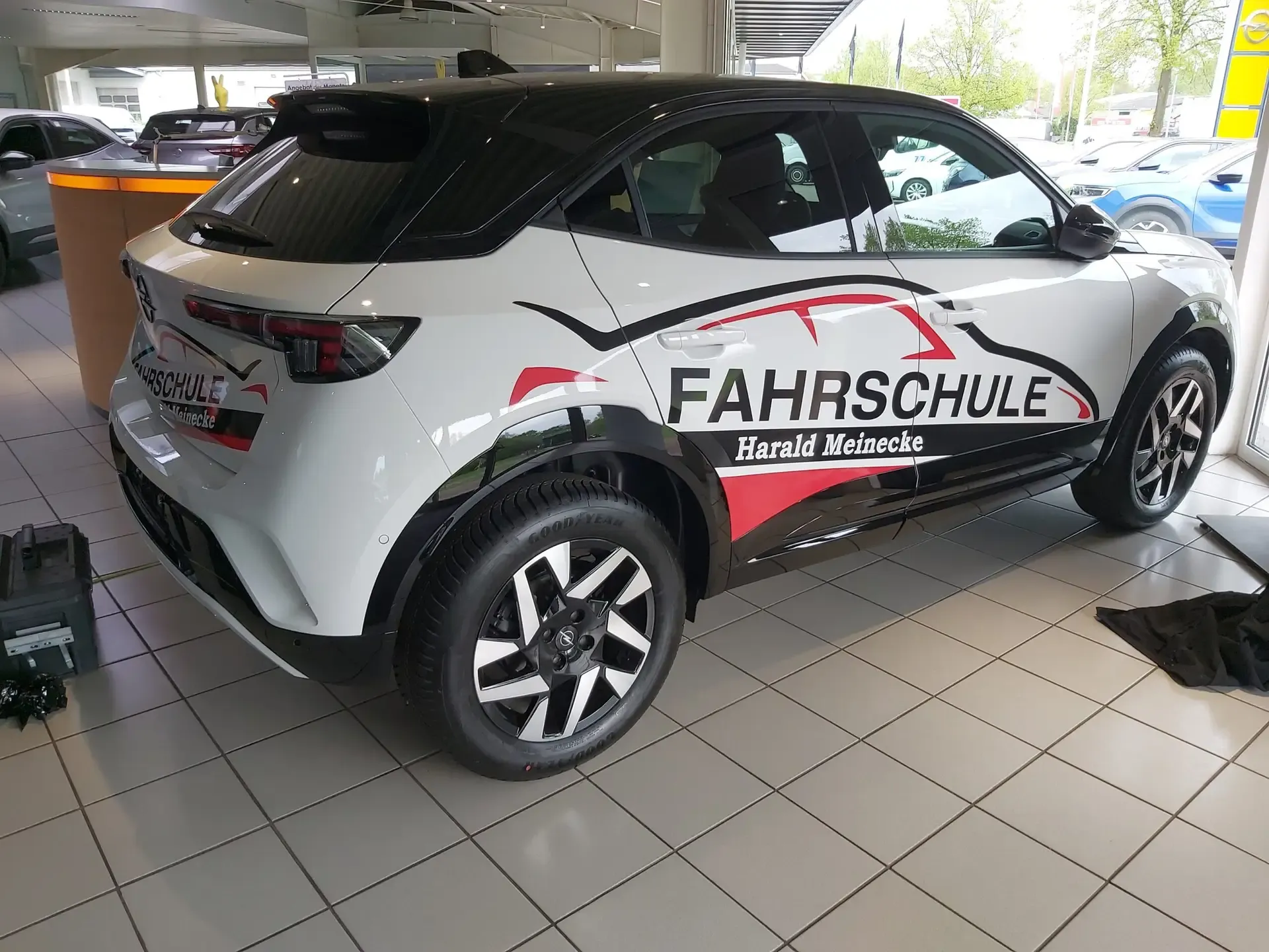 Weißes Fahrschulauto mit roter Beschriftung im Autohaus
