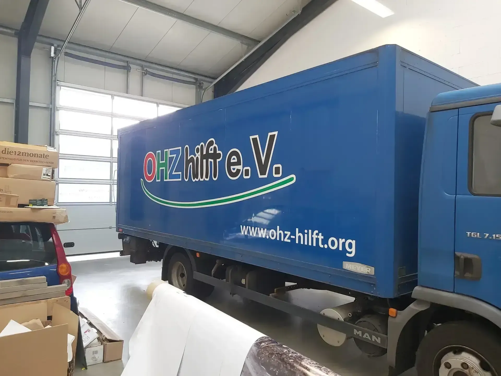 Blauer LKW mit Beschriftung eines Vereins in der Werkstatthalle
