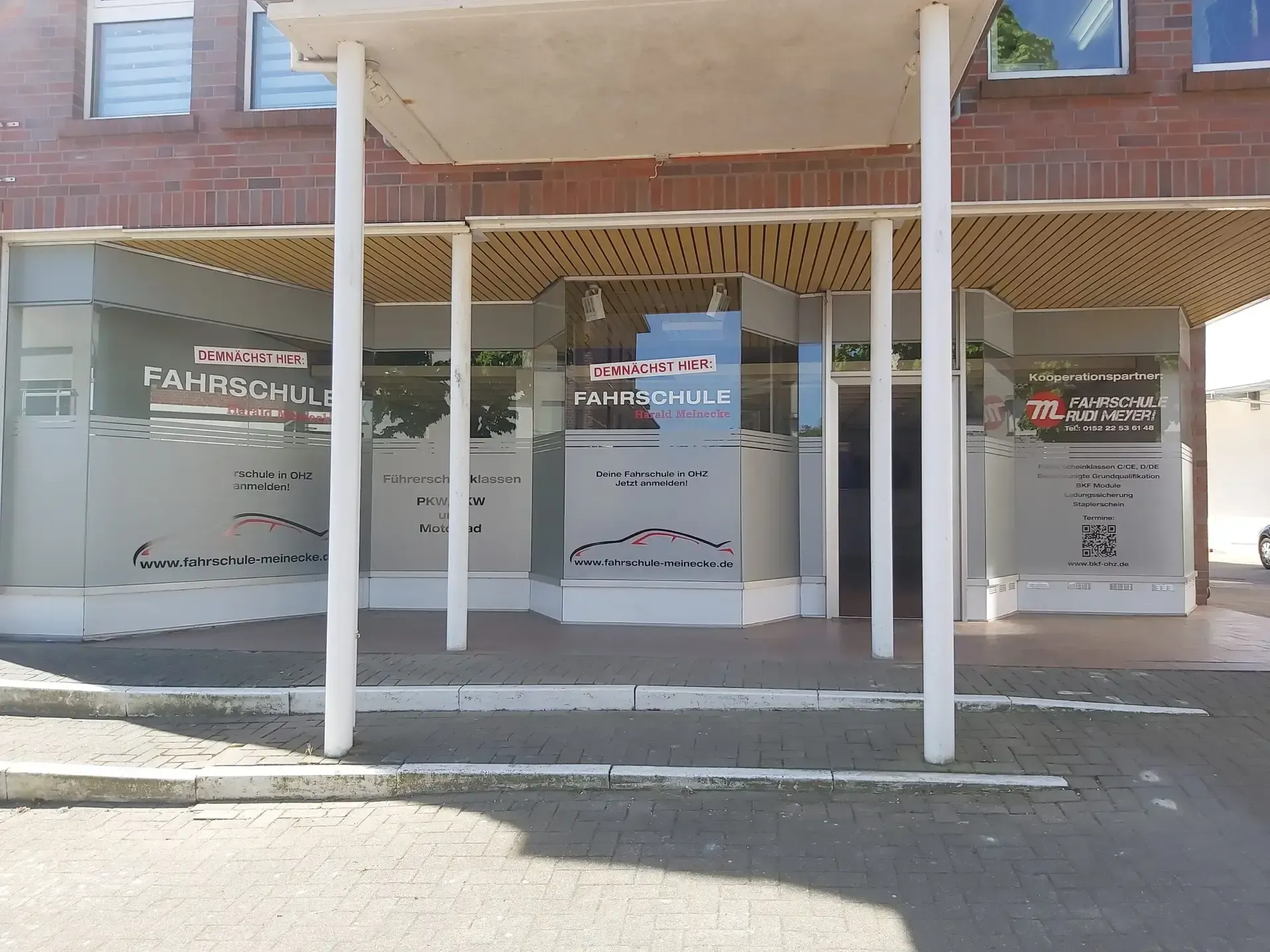 Beschriftete Schaufenster einer Fahrschule unter einem Vordach