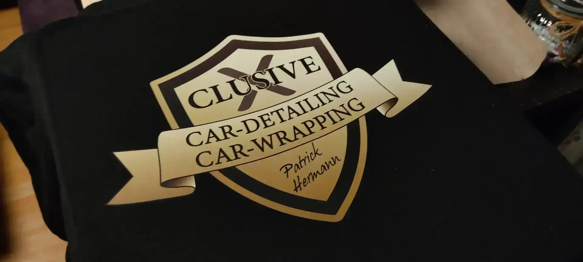 Schwarzer Stoff mit goldenem Logo eines Car-Detailings