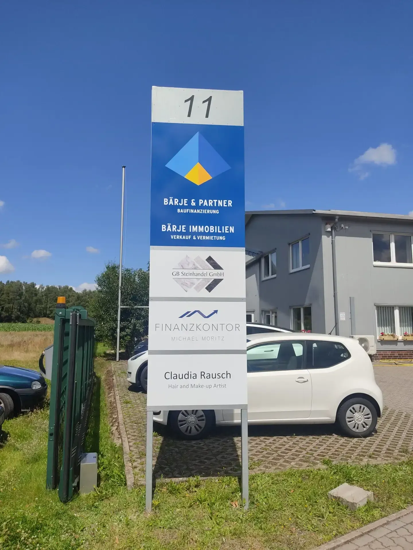 Hoher Werbepylon mit mehreren Firmenschildern vor einem Bürogebäude