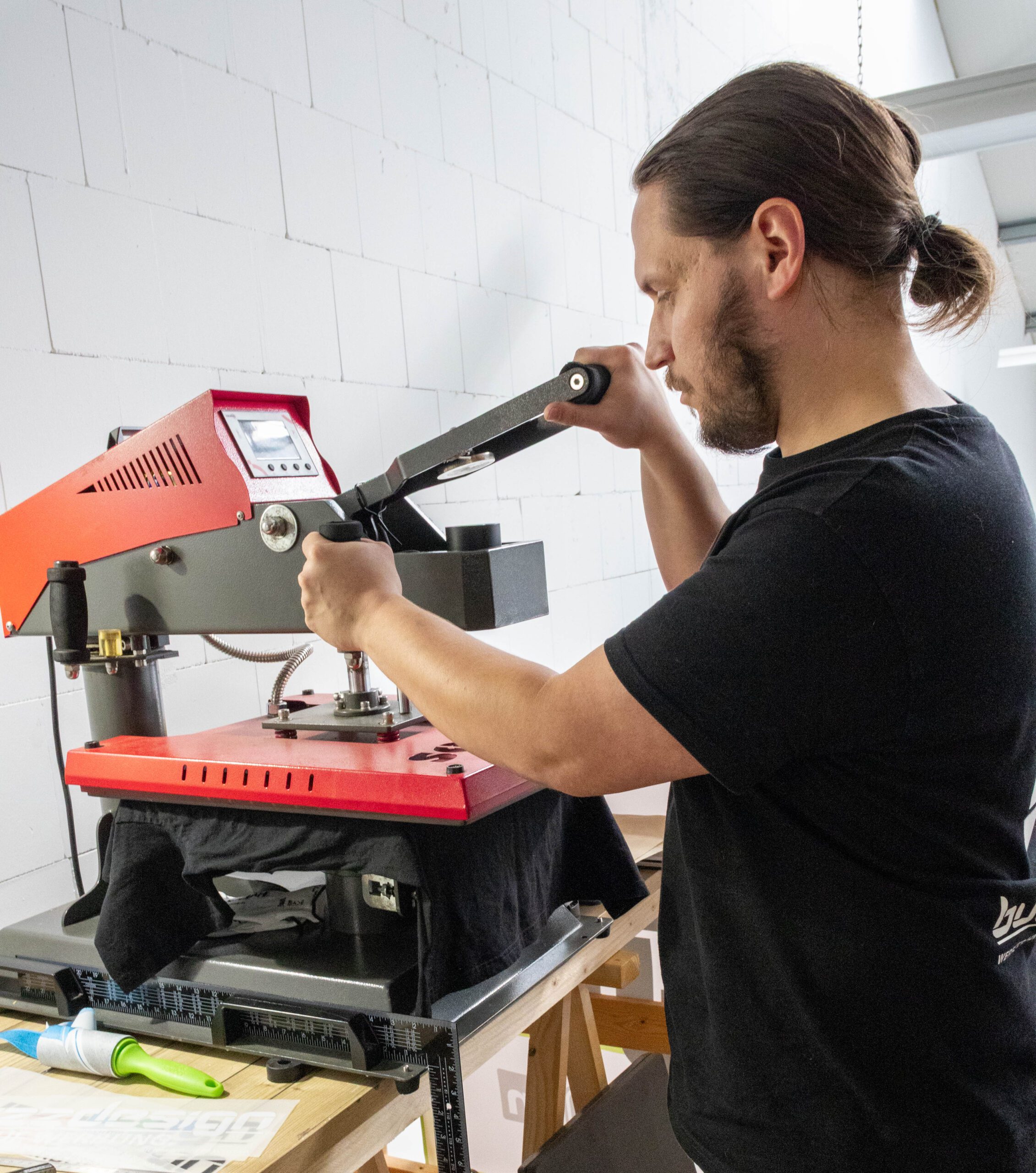 Sebastian Bock von buzzdesign beim Bedrucken eines T-Shirts mit einer Textilpresse.